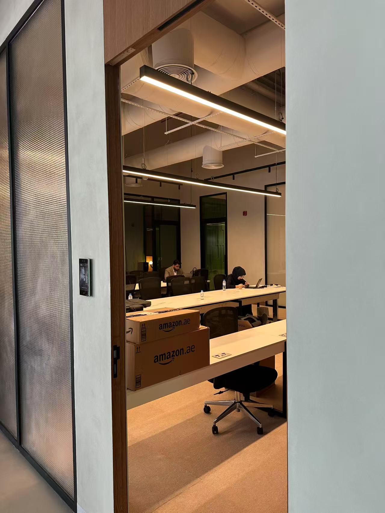 modern office workspace lighting in Dubai with linear pendant LED lights above collaborative desks