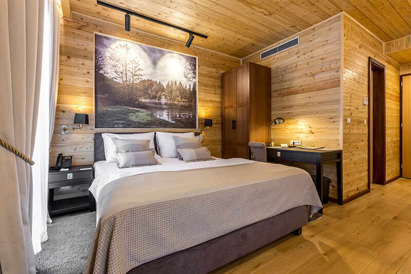 Croatian hotel guest room lighting using track lighting and wall lamps for warm hospitality atmosphere.