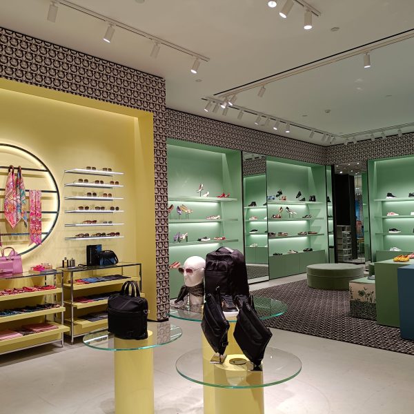 Dior boutique store interior illuminated with track spotlights and decorative wall lighting.